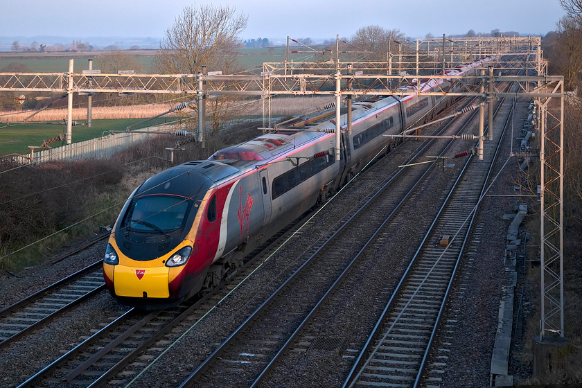 390117, VT 06.27 Wolverhampton-London Euston (1B03, 7L), Hungate End SP784465 
 390117 'Virgin Prince' speeds through the freezing cold early morning air as it passes Hungate End just near to Hanslope Junction on the lower WCML. This Pendolino was working the 1B03 06.27 Wolverhampton to London Euston. Notice that 390117 has a recently fitted replacement drawbar cover with yellow paint that is a very poor match! To get to this location requires quite a walk down a track for about a mile as there is no vehicle access allowed. 
 Keywords: 390117 1B03, 7L Hungate End SP784465