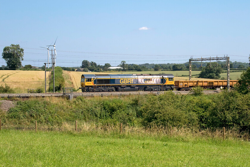 66739, 22.27 Willesden West London Junction-Bescot Yard (6G50, 3L), Roade Hill 
 High summer in south Northamptonshire! With just one small and lone cloud in an otherwise clear blue sky GBRf's 66739 'Bluebell Railway' passes Roade Hill between Milton Keynes and Northampton. It is leading the 6G50 22.27 Willesden to Bescot engineering train returning from overnight work in the north London area. Whilst it's nice to be out and about in such weather this image illustrates the perils for the photographer with very deep shadows, almost over-saturation and intense reflection that nearly made identification of the locomotive's number impossible! 
 Keywords: 66739 22.27 Willesden West London Junction-Bescot Yard 6G50 Roade Hill Bluebell Railway