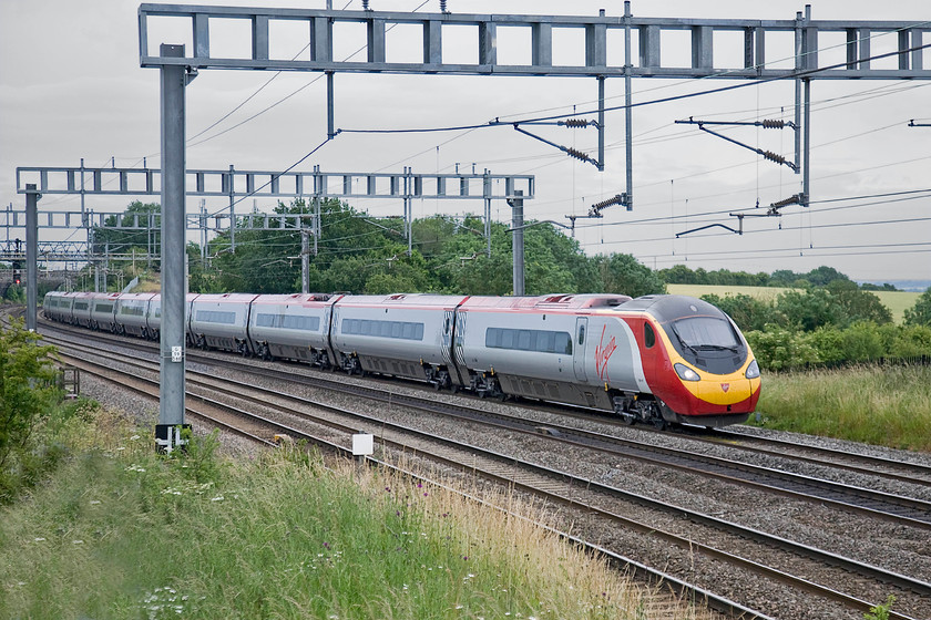 Class 390, VT 08.20 London Euston-Manchester Piccadilly (1H01), Ashton Road bridge 
 Under very grey skies for the start of July an eleven-car Virgin Pendolino passes between Roade and Ashton on the southern WCML with the 08.20 Euston to Manchester. 
 Keywords: Class 390 08.20 London Euston-Manchester Piccadilly 1H01 Ashton Road bridgeVirgin Trains Pendolino