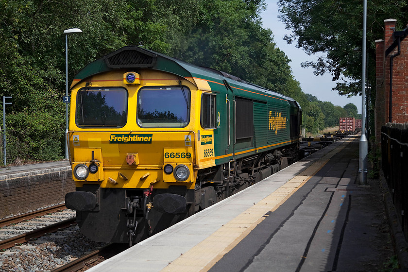 66569, 14.17 Southampton-Hams Hall (4M67), Dean station 
 66569 leads the 14.17 Southampton to Hams Hall Freightliner at some speed through Dean station. I am standing in Wiltshire but the majority of the train is still in Hampshire with the county boundary cutting through somewhere around the third flat waggon! 
 Keywords: 66569 4M67 Dean station