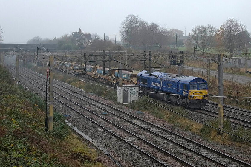 66148 & 66106 11.50 North Wembley Junction-Bescot (6R01, 18L), site of Roade station 
 66148 'Maritime Intermodal THREE' brings up the rear of the 11.50 North Wembley to Bescot engineering train past the site of Roade station. 66106 is out of sight at the front having passed under the village's former A508 road bridge. Time to head home for a cup of tea! 
 Keywords: Maritime Intermodal THREE