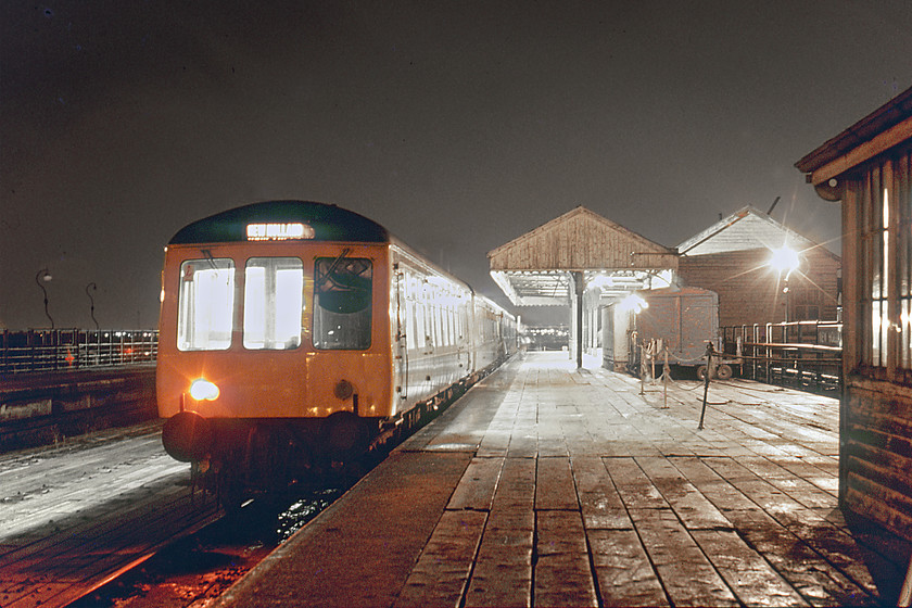 Class 114 DMU, 17.57 Cleethorpes-Barton-on-Humber, New Holland Pier station 
 With the snow now settling a Class 114 DMU is seen on New Holland pier jutting some one thousand four hundred feet into the Humber. The DMU has just arrived with the 17.57 from Cleethorpes. Train services were timed to arrive and depart in connection with the ferry sailings to and from Hull. Notice the small and now closed signal cabin to the extreme right. Following the removal of the second track on the pier the box was closed with the line operated as a long siding to and from Oxmarsh signal box. 
 Keywords: Class 114 DMU 17.57 Cleethorpes-Barton-on-Humber New Holland Pier station First-generation DMU