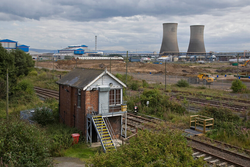 Belasis Lane signal box (NE, 1929) 
 A truly industrial scene on the north bank of the River Tees sees the CF fertiliser factory dominating the background who specialises in the manufacturing of things such as Ammonium Nitrate. Also in the background, between the two larger CF fertiliser buildings is the famous Middlesborough transporter bridge. In the foreground is the superb NER Belasis signal box that controls the twin-track siding from the junction with the mainline at Billingham Junction to the Haverton Hill chemical plant at Seal Sands. Notice that this 1929 box is over a later and simpler design with a simple gabled rather than the more complex (and expensive) hipped roof of the earlier types. It appears that the box is unmanned at the time of our visit with the rather substantial roller shutter firmly down protecting the door! 
 Keywords: Belasis Lane signal box North Eastern Railway