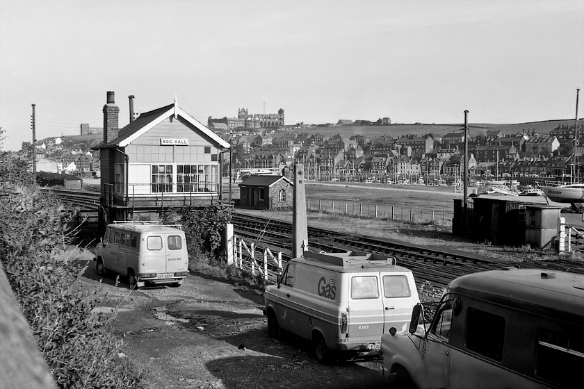 Bog Hall Signal Box (NER, Date not known) & crossing 
 A view of Bog Hall signal box looking back towards Whitby town with its famous seventh-century abbey on the skyline. The signal box was open and ins use on the day of my visit in 1980 but it was more commonly found to be switched ou being only a few hundred yards from Whitby box just around the corner to the left. The flat land beyond the box is now covered by a huge car park with the marina beyond and to the right much expanded. The level crossing has now been downgraded to a pedestrian foot crossing. I suspect all three of the vehicles have also gone. The 'T' registered BR Sherpa van was last on the road on 1986 but even when this was taken it was probably already rusting well! The Gas board Transit van may have survived a little better and was an infinitely superior drive than the Sherpa. Finally, note the former ambulance to the extreme right that I believe to be a Bedford J Series version with the conversion undertaken by Herbert Lomas of Wilmslow. 
 Keywords: Bog Hall Signal Box crossing NER North Eastern Railway