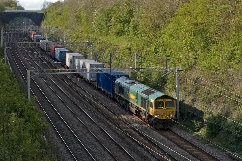 66951, 13.06 Ditton-Felixstowe North (4L92, 2L), Hyde Road bridge 
 It's teatime and the last day of April so the sun is just able to still reach the depths of Roade cutting. It just manages to illuminate the flank of the 4L92 13.06 Ditton to Felixstowe Freightliner led by 66951. This particular 66 was the first of five that arrived in the UK in 2004 that were being evaluated as low-emission versions of the class. With ever more stringent emission regulations as further members of the class were ordered the lessons learnt from these early five examples were used to make the later locomotives compliant. 
 Keywords: 66951 13.06 Ditton-Felixstowe North 4L92 Hyde Road bridge Freightliner