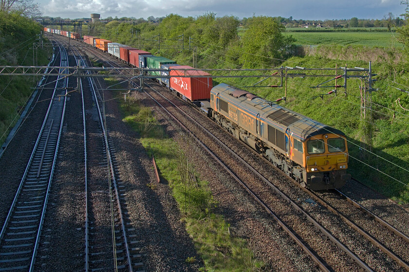 66753, 13.57 Birch Coppice-London Gateway (4L68, RT), Victoria bridge 
 Looking uncharacteristically unkempt (for a GBRf locomotive that is) 66753 'EMD Roberts Road' leads the 4L68 13.57 Birch Coppice to London Gateway service. The dark and dramatic sky above the village of Roade contrasts well with the brightly lit foreground, a scene typical of a British April day! 
 Keywords: 66753 13.57 Birch Coppice-London Gateway 4L68 Victoria bridge EMD Roberts Road