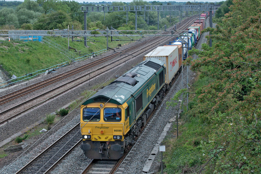 66590, 09.25 Southampton-Garston (4M28, 17E), Ashton Road bridge 
 After a lovely start to the day, by lunchtime, it had clouded over and as can be seen in this photograph at Ashton Road bridge just south of Roade it was rather dull. Running late, 66590 leads the 09.25 Southampton to Garston Freightliner on the down fast already with no fewer than four Pendolinos stacking up behind signal to signal. The reason for this unusual move by control to allow a slow freight onto the fast line was due to the failure of 4L94 hauled by 66415 'You Are Never Alone' near to Long Buckby earlier in the afternoon blocking the northbound Northampton loop. 
 Keywords: 66590 09.25 Southampton-Garston 4M28 Ashton Road bridge Freightliner