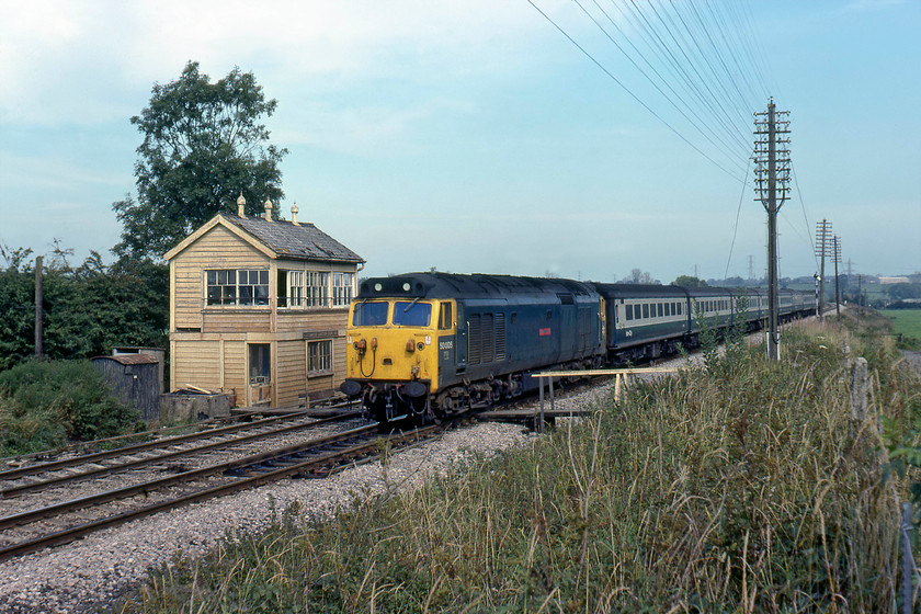 50005, 12.23 London Paddington-Paignton (1B74), Blatchbridge Junction 
 The 1938-built 28-lever type 28B Blatchbridge signal box was of all timber construction and in a pretty remote spot to the south of Frome. The line into the town, that emerged on to the mainline again at Clink Road Junction, curved away to the left behind the fourth coach of the train in this image. Note that the box still retains its GWR cast sign, however, in a shot taken just over a year later, this had been replaced by a BR corporate sign, I wonder where it ended up? 50005 'Collingwood' heads westwards leading the 12.23 Paddington to Paignton 1B74 train. At the time of writing in 2019, this train is now worked by a class 800 IET. 
 Keywords: 50005 12.23 London Paddington-Paignton 1B74 Blatchbridge Junction