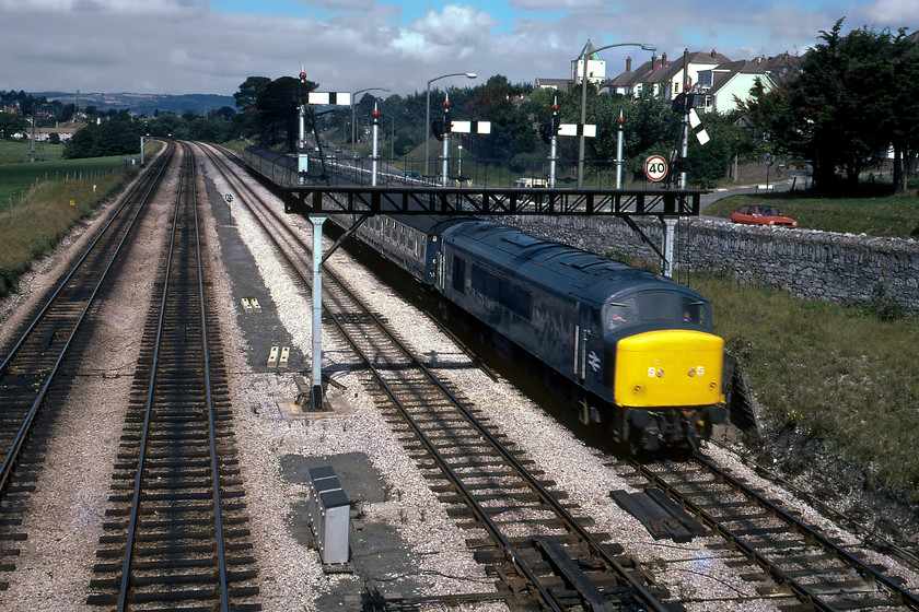 45013, 08.55 Cardiff Central-Paignton (1B18), Aller Junction 
 45013 nears journey's end at Aller Junction leading the 08.55 Cardiff to Paignton service. It is passing under Aller Junction's impressive four-doll gantry that spans to pair of down lines. With four semaphores either the Paignton or Plymouth down can be accessed from both lines. As D20 45013 was new to service in February 1961 making it nineteen years old when seen here in glorious Devon! It continued in service for another seven years eventually being cut up at Springburn in 1994. Notice the natty Mk. 1 Ford Fiesta passing along the A380 racing the train, with its black vinyl roof and side stripes I suspect that it was an S model making the car a maximum of two years old when this photograph was taken. 
 Keywords: 45013 08.55 Cardiff Central-Paignton 1B18 Aller Junction Peak