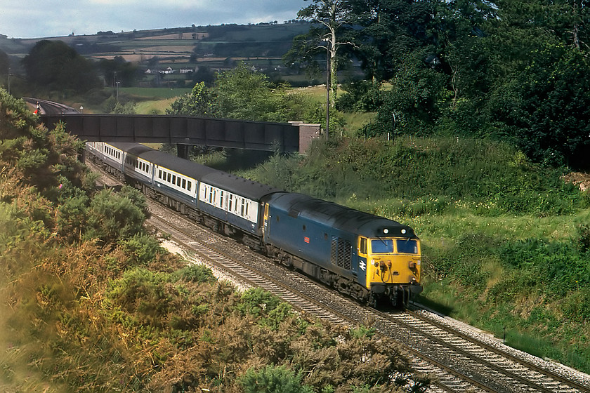 50021, 06.24 Penzance-London Paddington, Whiteball ST082173 
 In the early morning summer sun, 50021 'Rodney' makes a heck of a racket as it ascends Whiteball from the west with the 06.24 Penzance to London Paddington. This picture is taken from a field close to where I camped just behind the signal box. This was a very remote and quiet spot with just the sounds from the signal box for company. The small village of Burlescombe can be seen in the background above the bridge. 
 Keywords: 50021 06.24 Penzance-London Paddington Whiteball ST082173