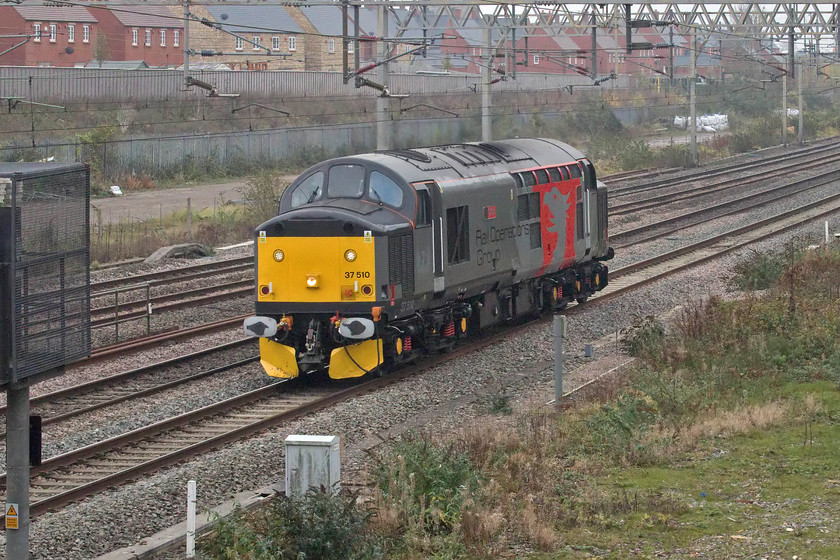 37510, 12.10 Wembley HS-Leicester LIP (0VXX, 40E), site of Roade station 
 I had to run in order to capture 37510 'Orion' working the 12.10 Wembley Yard to Leicester LIP as I suddenly realised that it was passing Milton Keynes - or so I thought! I did not spot that it was being held at Hanslope Junction awaiting its passage from the slow to the fast lines due to the closure of the Northampton route. Control went on to hold the locomotive for an age in fact, to the point, that by the time it passed me at Roade it was running fifteen minutes late! However, it was worth the wait as I have never photographed 37510 in this, its latest guise. If anybody can supply me with the reporting number of this working can you please contact me? 
 Keywords: 37510 12.10 Wembley HS-Leicester LIP 0ZXX site of Roade station Orion Europheonix