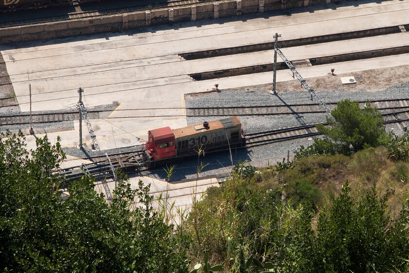 310 055, shunting, Barcelona Harbour, from Montjuc Castle 
 The Class 310 XXX date from the late 1980s and early 1990s being built by Meinfesa with General Motors Electromotive Division components in the form of engines and electrical transmissions. 310 055 is one of sixty built with a number now modified and reclassified and is seen from the ramparts of Barcelona's Montjuc Castle idling below in the harbour complex. 
 Keywords: 310 055 shunting Barcelona Harbour from Montjuc Castle