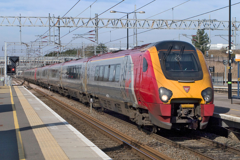 221114 & 221106, VT 06.52 Edinburgh Waverley-London Euston (9M50), Milton Keynes Central station 
 Warning.......a repeat moan coming up! A pair of Voyager diesel units in the form of 221114 'Sir Walter Raleigh' and 221106 'Willem Barents' have just travelled all the way from Edinburgh Waverley under fully energised 25kv wiring.....why? The train is seen sweeping through Milton Keynes Central as the 06.52 Edinburgh to Euston under glorious early spring skies. 
 Keywords: 221114 221106, VT 06.52 Edinburgh Waverley-London Euston (9M50), Milton Keynes Central station