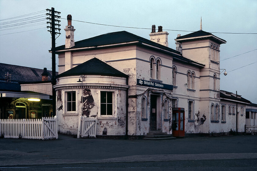 Frontage, Gobowen station 
 On our long journey home from Bangor to Bath Graham and I made one more railway-related stop in the dusk at Gobowen. There was just enough light to take a long exposure of an image of the unusual station building probably utilising Graham's tripod. Back in 1981 the station was looking particularly run down and in need of some attention. Designed by Thomas Mainwaring Penson the building is now Grade II listed which affords it a degree of protection with it now fully restored. It was built between 1846 and 1848 by the Shrewsbury and Chester Railway in a notable Florentine (or Italianate) style with white stucco facing and a small turret. Today it is in use containing a number of business units and is a notable structure within the town. 
 Keywords: Frontage Gobowen station