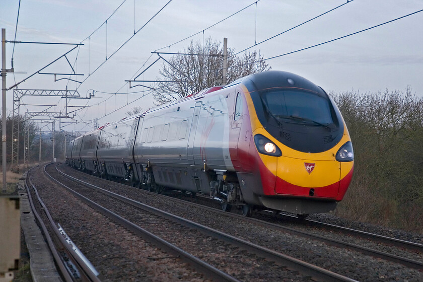 Class 390, VT 06.10 Manchester Piccadilly-London Euston, Bugbrooke SPO676565 
 Catching some early morning light the 06.10 Manchester to Euston Virgin service passes near Bugbrooke on the Northampton avoider route (known as the old line) worked by an unidentified Class 390 Pendolino. After the long months of deep winter by the middle of February the daylight hours are extending enough to take photographs before 08.00. 
 Keywords: Class 390 06.10 Manchester Piccadilly-London Euston Bugbrooke SPO676565 Virgin West Coast Pendolino