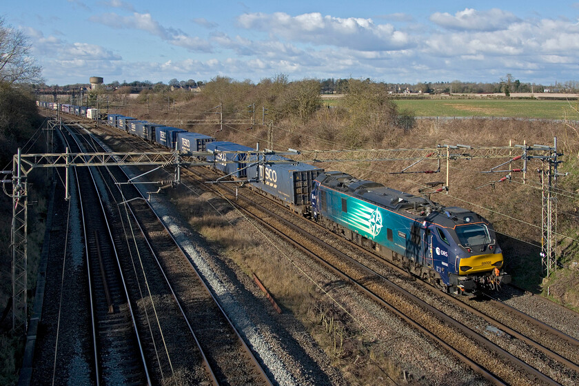 88006, 13.37 DIRFT-Tilbury FLT (4L48, 11L), Victoria bridge 
 The daily afternoon 4L48 Tesco Express passes Victoria bridge between Roade and Ashton led by 88006 'Juno'. This seven-day-a-week service from Daventry to London Gateway is often electric hauled, identified by the shorter time that it takes to get from Northampton to this location. When diesel-hauled, the train labours on the steady climb from Northampton taking considerably longer than when a Class 88 is at the helm. 
 Keywords: 88006 13.37 DIRFT-Tilbury FLT 4L48 Victoria bridge Tesco Express Juno