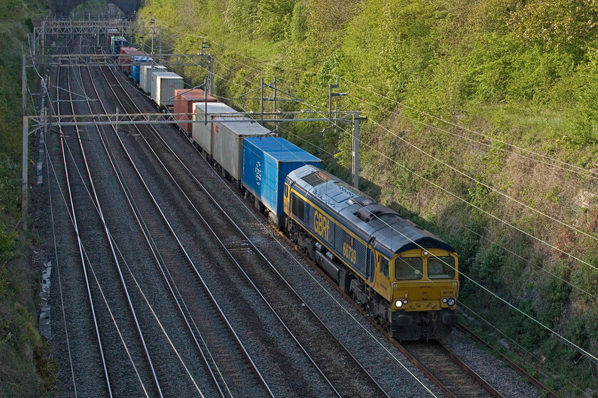 66739, 13.39 Ditton-Felixstowe North (4L62, 3E), Hyde Road bridge 
 With the sun sinking fast the final vestiges of the day's bright and welcome April light are struggling to reach reach the depths of Roade cutting. There is just enough light to to illuminate 66739 'Bluebell Railway' as it heads south working the 13.39 Ditton to Felixstowe North Freightliner. 4L62 is one of six freights that are due to pass through Roade within a forty-five minute period at around teatime on weekdays. Is there anywhere else on the mainline where this is the case I wonder? 
 Keywords: Bluebell Railway 66739 13.39 Ditton-Felixstowe North 4L62 Hyde Road bridge