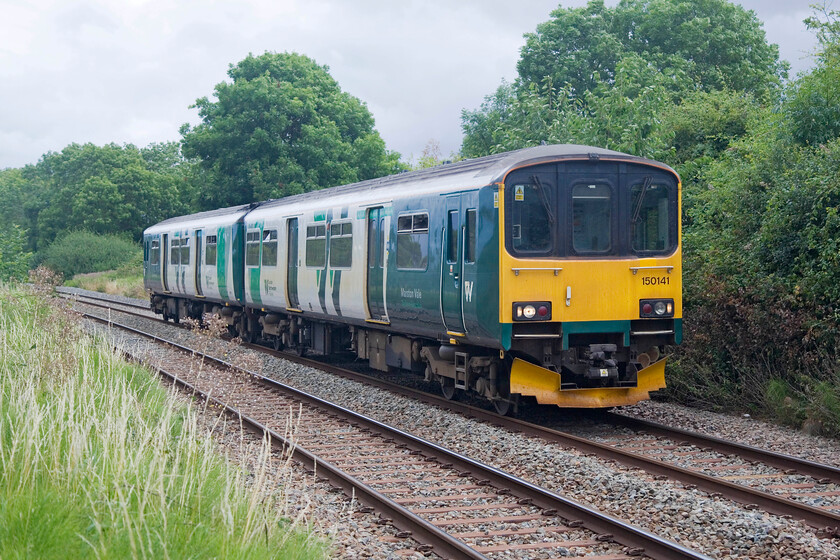 150141, LN 09.47 Bedford-Bletchley (2S08, 2L), Lidlington SP984387 
 With a toot from the driver, the 09.47 Bedford to Bletchley service is seen accelerating away from Lidlington station worked by veteran DMU 150141. I am standing on the railings of a foot crossing that will no doubt be closed soon as NR continues with its obsessive plan to rid its network of any points of access. If the East West Rail programme is ever to be extended eastwards from Bletchley (but now looking increasingly unlikely under the new Labour Government's plans) then this section of line will become a hundred-mile-per-hour mainline. 
 Keywords: 150141 09.47 Bedford-Bletchley 2S08 Lidlington SP984387 London Northwestern