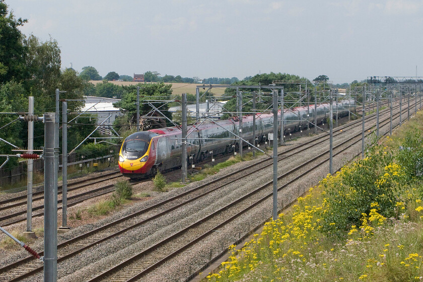 390155, VT 13.30 London Euston-Glasgow Central (1S69), Lichfield Nether Stowe footbridge 
 390155 'X-Men: Days of Future Past' speeds northwards from Lichfield's Nether Stowe footbridge working the 13.30 Euston to Glasgow Central train. This Pendolino was named at Euston station some four months ago as part of a promotional exercise with two of the film's actors, Hugh Jackman and James McAvoy, attending the launch. Notice the chimney of Rugeley power station just in view to the left of the photograph emerging from trees. 
 Keywords: 390155 13.30 London Euston-Glasgow Central 1S69 Lichfield Nether Stowe footbridge Virgin Pendolino X-Men: Days of Future Past