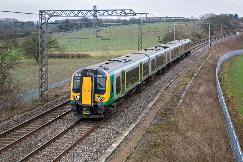 350117, LM 11.24 London Euston-Birmingham New Street, Milton crossing 
 350117 takes the Weedon line thus avoiding Northampton forming the 11.24 Euston to Birmingham New Street service. It is routed this way due to engineering works in the Northampton area. The cloudy and overcast conditions are in stark contrast to my visit to the same location just three hours earlier. 
 Keywords: 350117 LM 11.24 London Euston-Birmingham New Street Milton crossing Desiro London Midland