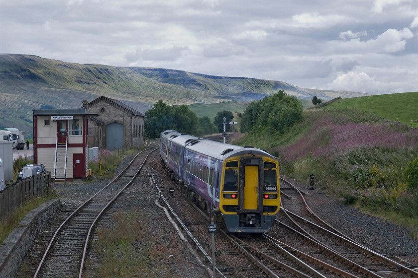 158844 & 158877, NT 14.04 Carlisle-Leeds (2H93), Kirkby Stephen station 
 Again I have missed the sun! With the fells in the background dominated by the dramatic Mallerstang Edge 158844 and 158877 accelerate away past Kirkby Stephen signal box and the former goods shed. The pair of Northern units are working the 14.04 Carlisle to Leeds train that will continue its accent of the Long Drag over the Settle and Carlise route. 
 Keywords: 158844 158877 14.04 Carlisle-Leeds 2H93 Kirkby Stephen station Northern