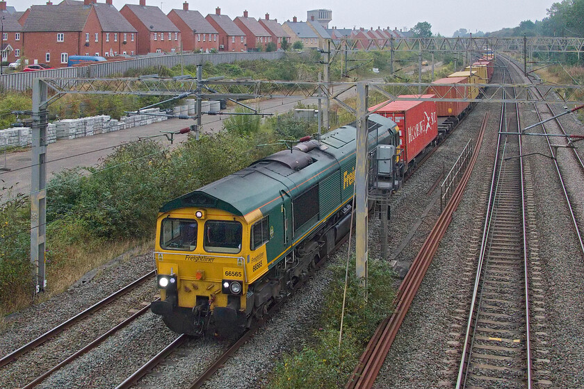 66565, 02.57 Felixstowe North-Garston (4M45, 36E), site of Roade station 
 66565 passes Roade leading the 02.57 Felixstowe to Garston 4M45 Freightliner. This is not a view that I normally use as it requires the camera's flip screen to be opened up and me holding the camera at full arm's length over the parapet extension; how the normals crossing the footbridge stare! If the skies had been clear this shot would have been disastrous as it would be straight into the rising sun! This 66 is one that has the yellow visibility panel extended down on to the buffer beam unlike most of the other members of the class; it looks odd like this in my eyes. 
 Keywords: 66565 02.57 Felixstowe North-Garston 4M45 site of Roade station Freightliner