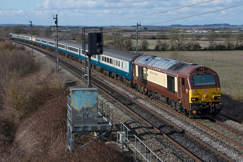 67024 & 67005, 08.43 Newcastle Central-Wembley Central (1Z43, 6L), Milton crossing 
 In superb winter lighting 67024 leads the late running 1Z43 footex past Milton Crossing just north of Roade. 67005 'Queen's Messenger' is on the rear of the matching set of BR blue stock with the exception of a Mk.I buffet car. The train left Newcastle at 08.43 and was taking hopeful Newcastle supporters to Wembley to cheer on their team who were competing in the EFL Cup against Manchester United. Unfortunately, their journey home would have been a little muted as Newcastle were defeated 2-0. 
 Keywords: 67024 67005, 08.43 Newcastle Central-Wembley Central 1Z43 Milton Crossing