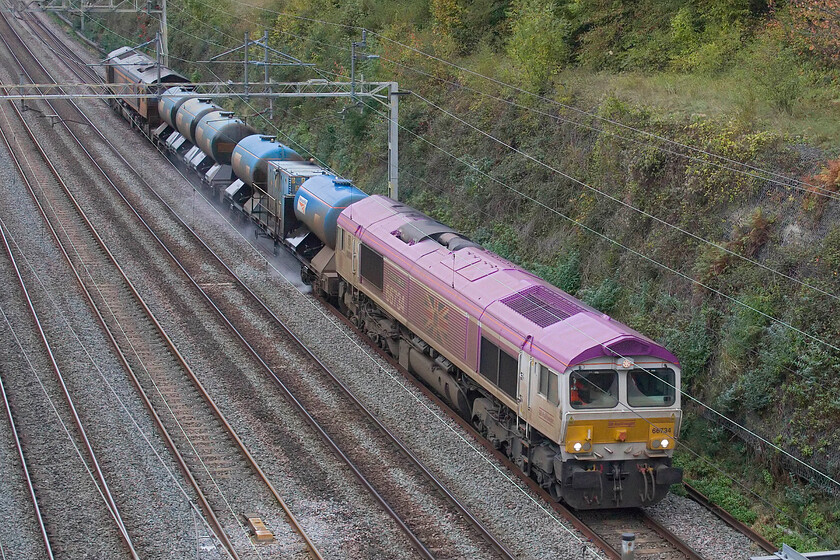 66734 & 66766, 10.30 King's Norton-King's Norton (3J01, 4E), Hyde Road bridge 
 In past years I have not managed many photographs of RHHT (RailHead Treatment Trains) close to home as their timings have not been favourable. However, this leaf fall season (or should we simply call it autumn?) the 3J01 10.30 King's Norton return service passes close to home in the late afternoon. Seen passing under Roade's Hyde Road bridge the train is seen led by 66734 'Platinum Jubilee' with 66766 'Gail Richardson' catching the filthy spray at the rear. 
 Keywords: 66734 66766 10.30 King's Norton-King's Norton 3J01 Hyde Road bridge RHTT Platinum Jubilee Gail Richardson