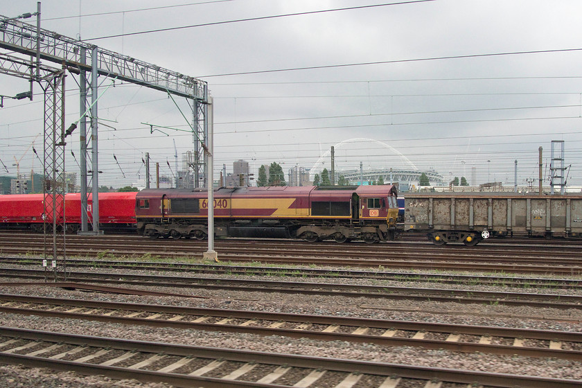 66040, up-spoil train, Wembley yard 
 66040 waits at the head of an unidentified spoil train in Wembley yard. In the background is Wembley stadium that would host the FA cup final the following day between nearby Watford and Manchester City. 
 Keywords: 66040 up-spoil train Wembley yard