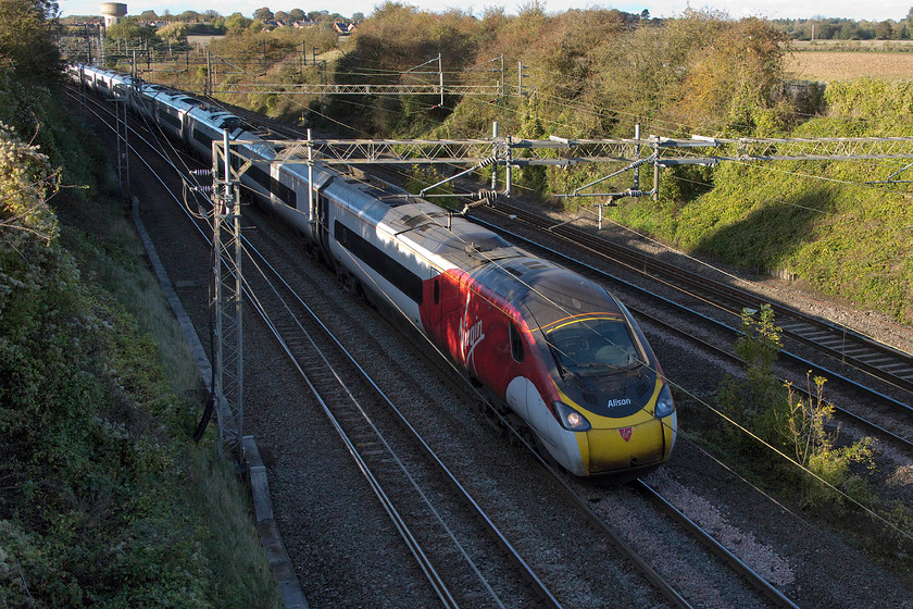 390115, VT 12.47 Liverpool Lime Street-London Euston (1A30, 1L), Victoria bridge 
 390115 'Crewe-All Change' rounds the curve just south of Roade and is about to pass under Victoria bridge. The sun is just managing to catch the top of some of the carriages with it getting lower in the sky day by day, this being the first afternoon after changing the clocks from British summertime. Notice the name Alison applied to the front of the Pendolino. This was applied at the same time as the train was named at Crewe station on June 8th to the memory of former station staff member Alison Austin who lost her battle with cancer last year. 
 Keywords: 390115 12.47 Liverpool Lime Street-London Euston 1A30 Victoria bridge