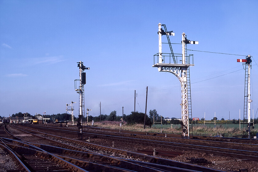 Signalling, Ely South 
 Quite how Graham and I got access to the vast south yard at Ely I am not sure, I believe that we just walked down the edge of the sidings in the early evening light and took our photographs! In this view, looking northeast, the station is seen in the distance with the 17.30 Ely to Cambridge DMU waiting to leave worked by what looks like a Class 105 Cravens unit. To its right, the flat end of 08083 is seen going about its business. The scene is dominated by a marvellous collection of semaphores that would be controlled by Ely Dock Junction which would be to my right shoulder in this view. Notice the Eastern Counties red bus heading out of town along Bridge Road towards Newmarket. 
 Keywords: Signalling Ely South