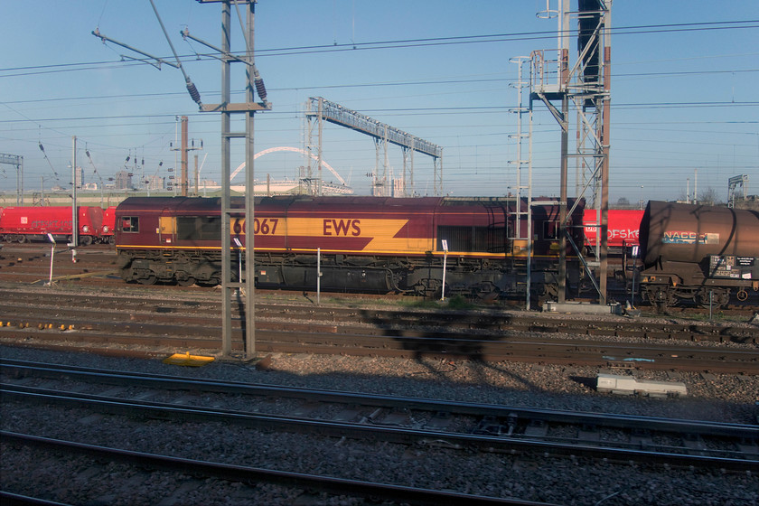 66067, stabled, Wembley yard 
 With Wembley stadium's lattice arch at 436 feet high dominating the background 66067 sits in the yard awaiting its next duty. The arch is the world's longest unsupported roof structure being part of the national stadium that was designed by the architects Foster and Partners and that opened in March 2007. 
 Keywords: 66067 Wembley yard EWS DBS