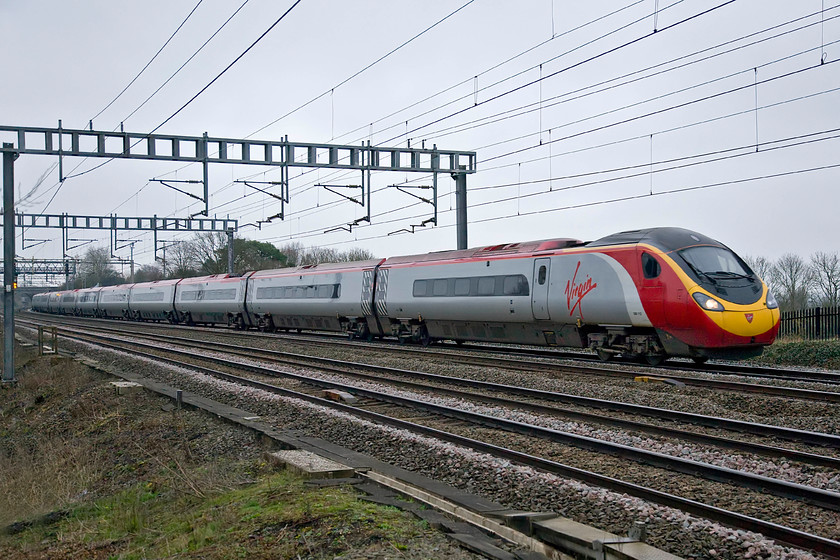 390112, VT 07.20 London Euston-Manchester Piccadilly (1H09), Ashton Road bridge 
 The 07.20 Euston to Manchester Piccadilly Virgin Trains service passes between Roade and Ashton worked by 390112. After last Saturday's bright and frosty morning, exactly a week later today the weather is somewhat different! 
 Keywords: 390112 07.20 London Euston-Manchester Piccadilly 1H09 Ashton Road bridge Virgin Pendolino