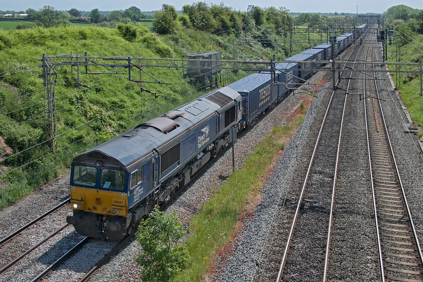 66427, 04.00 Tilbury Docks-DIRFT (4M77), Victoria bridge 
 Running extremely late the 4M77 northbound Tesco Express passes Victori bridge just south of Roade. The 04.00 Tilbury to Daventry (DIRFT) service normally passes this spot around dawn meaning it is not a service that I have many photographs of. DRS' 66427 is leading the train that is seen in tricky lighting that necessitated a considerable amount of work in Photoshop. 
 Keywords: 66427 04.00 Tilbury Docks-DIRFT 4M77 Victoria bridge DRS Direct Rail Services Tesco Express