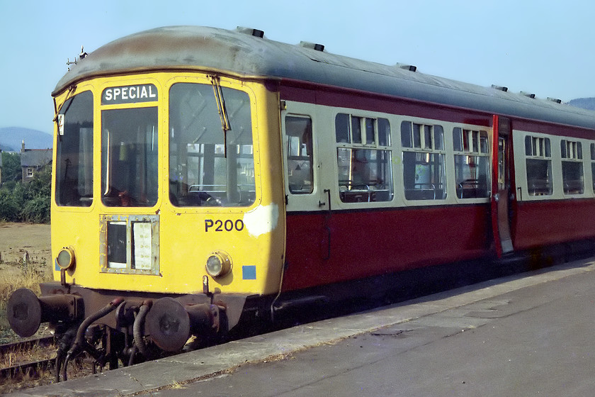 P200, stabled 
 With a parched field in the background, one of the WSR's resident class 103 Park Royal DMUs sits in the baking sun at Minehead. This one is painted in the WSR livery of the time and was in-service. The railway had opened to passengers earlier in 1976 with the 103s providing the backbone of their workings. Unfortunately, despite extensive research, I cannot find out the number of this car. Set P200 was a two-car unit that the WSR bought from BR when it was retired from use on the Kingswear branch following closure in 1972.