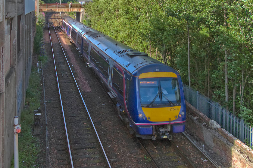 170404, SR 15.33 Aberdeen-Glasgow Queen Street (1T34), Arbroath Wellgate level crossing 
 Taken from the lofty heights of the latticed cast-iron footbridge at Wellgate level crossing 170404 slows for its stop at Arbroath with the 15.33 Aberdeen to Glasgow Queen Street ScotRail service. Unfortunately, the train is entirely in the shade as the sun has got low in the sky and is obscured by the large building to the left. Until relatively recent times there was another large factory to the right in the scene where the saplings are now growing. 
 Keywords: 170404 15.33 Aberdeen-Glasgow Queen Street 1T34 Arbroath Wellgate level crossing ScotRail