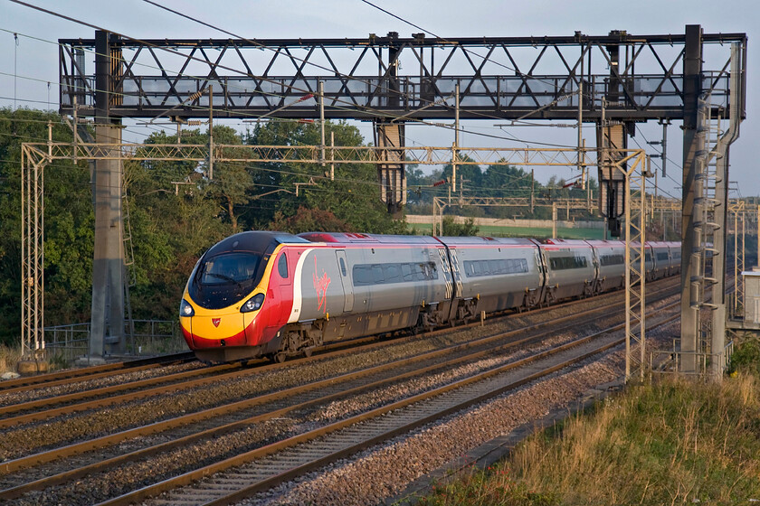 390125, VT 05.27 Liverpool Lime Street-London Euston (1R05), Roade Hill 
 The 05.27 Liverpool to Euston Virgin service passes between Roade and Ashton on the southern WCML with just over half an hour left of its journey from Merseyside. The train is being worked by a smart-looking 390125 catching the early morning sun now that it has risen well above the horizon behind me. 
 Keywords: 390125 05.27 Liverpool Lime Street-London Euston 1R05 Roade Hill Virgin West Coast Pendolino