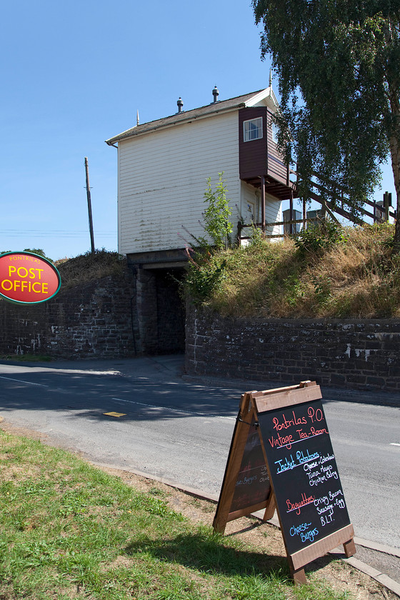 Pontrilas signal box (GWR, 1880) 
 The rear view of Pontrilas signal box reveals that it is situated atop a bridge that is actually a small and narrow tunnel under the line. Andy and I made good use of the Post Office, as seen in the picture, by buying ice creams in an attempt to cool us down on this now beltingly hot afternoon! 
 Keywords: Pontrilas signal box