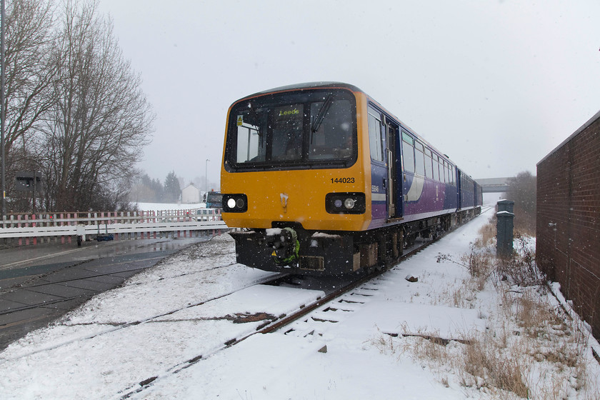 144023, NT 14.14 Knottingley-Leeds (2F20, 4L), Cutsyke level crossing 
 With he snow beginning to come down again, 144023 crosses Cutsyke level crossing at the 25mph speed limit as it's about to take the sharp right hand curve just after it and on up to Castleford station. This Pacer dates from the mid 1980s and is very much nearing the end of the literal line as this picture was taken in 2018. 
 Keywords: 144023 2F20 Cutsyke level crossing