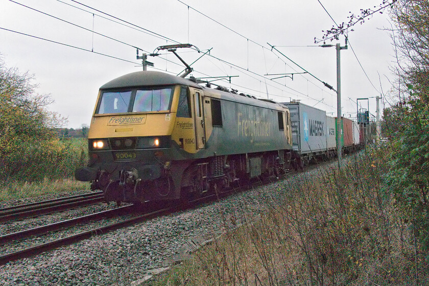 90043, 04.57 Trafford Park-Felixstowe North (4L97, 1L), Watford SP614688 
 Due to a very high spike in electricity prices, Freightliner sidelined their electric fleet in favour of diesel haulage but they appear to have reversed this if this view near Watford village (Northamptonshire) is anything to go by. 90043 is seen heading south leading the 4L97 04.57 Trafford Park to Felixstowe service. The light was atrocious at this isolated foot crossing with the camera really being pushed to the limits of its operation. 
 Keywords: 90043 04.57 Trafford Park-Felixstowe North 4L97 Watford SP614688 Freightliner