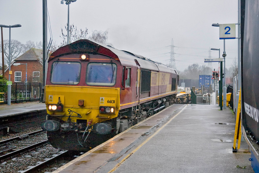 66131, 09.15 Trafford Park-Southampton (4O21), Bramley station 
 The camera has struggled to keep things under control in this photograph with the chronically bad lighting! Close examination of the dark areas revealed a lot of digital noise that I had to work on to make the image acceptable. 66131 passes through Bramley station leading the 09.15 Trafford Park to Southampton Freightliner service. I was hoping to get back to the van at this point until Andy pointed out that something far more interesting was due in the other direction...... https://www.ontheupfast.com/p/21936chg/29360076004/x13-66520-13-28-eastleigh-yard-hinksey 
 Keywords: 66131 09.15 Trafford Park-Southampton 4O21 Bramley station Freightliner EWS