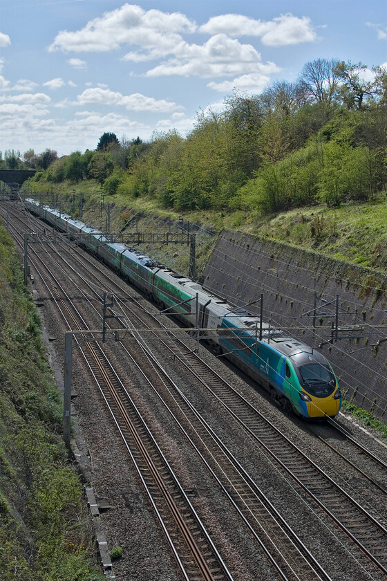 390121, VT 10.53 London Euston-Manchester Piccadilly (1H15, 12L), Roade cutting 
 Still proudly wearing its COP26 climate change vinyls 390121 'Opportunity' passes northwards through Roade cutting working the 1H15 10.53 Euston to Manchester Piccadilly. Despite the Avanti press launch of the train back in 2021 showing the two young people who's names were chosen for the Pendolino proudly lifting some proper 3D type of plates, as is the case now with most named trains only rather disappointing vinyl plates are actually applied. 
 Keywords: 390121 10.53 London Euston-Manchester Piccadilly 1H15 Roade cutting Virgon Avanti West Cast Pendolino opportunity