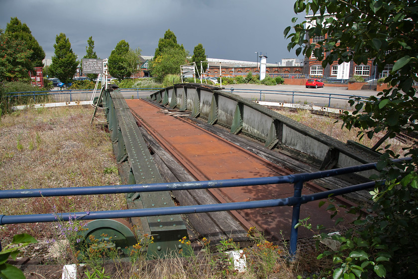 Former turntable, Swindon Works 
 The former turntable at Swindon Works. This turntable was right at the front in the centre of the vast works complex. The pattern building can be seen to the right behind the overhanging bush. 
 Keywords: turntable Swindon Works