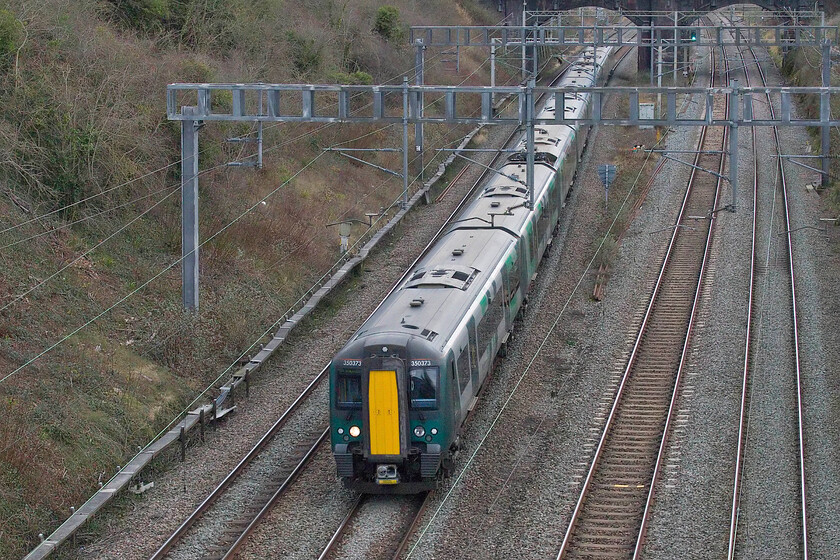 350373 & 350110, LN 12.56 London Euston-Birmingham New Street (1Y25, 9L), Hyde Roade bridge 
 Bridge 208 spans Roade cutting carrying the village's Hyde Road. In 2018 it had a Transport Trust wheel attached to it in recognition of the cutting as being a transport heritage site. Looking south from the bridge the 12.56 Euston to Birmingham London Northwestern service is seen worked by 350373 and 350110. 
 Keywords: 350373 350110 12.56 London Euston-Birmingham New Street 1Y25 Hyde Roade bridge London Northwestern Desiro