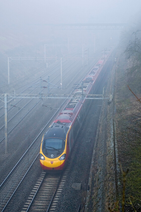 390104, VT 08.15 Liverpool Lime Street-London Euston, Roade cutting 
 390104 'Alstom Pendolino' emerges from the fog as it passes through Roade cutting. It is on the up slow line having avoided the Weedon route instead coming via Northampton. It is working the 08.15 Liverpool to Euston Sunday service that will have been suitably re-timed to take account of extra time due to the diversion. 
 Keywords: 390104 08.15 Liverpool Lime Street-London Euston Roade cutting Alstom Pendolino