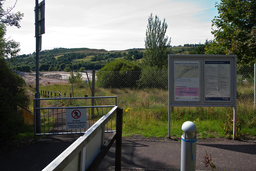 Pedestrian access, IBM station (demolition of factory underway) 
 In the middle distance to the left can be seen the flattened remains of the once huge IBM factory in Spango Valley southwest of Greenock. After much rationalisation, it closed in 2016 and became another nail in the coffin of Scotland's once famous 'Silicon Glen'. The station, named IBM, was opened in 1978 to serve the workforce and it did so successfully for many years. Even though trains are still scheduled to stop, they drop and collect no passengers except for possibly some contractors working on the site. 
 Keywords: IBM station