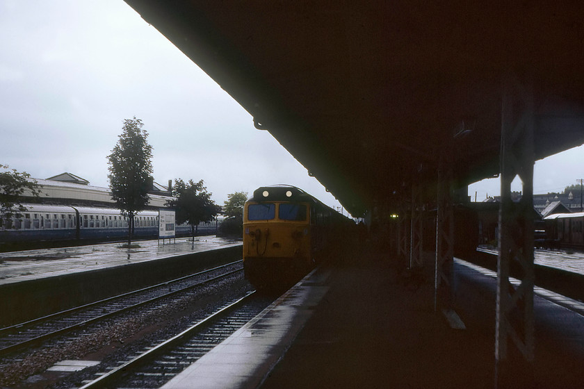 50029, 17.32 London Paddington-Penzance (1B22), Taunton station 
 In torrential rain, 50029 'Renown' slows for its stop at Taunton station with the 1B22 17.32 Paddington to Penzance. Kodachrome 64 film is really struggling here in the deplorable lighting just two days after the longest day! Note that the down bay platforms are still extant to the right. These came out of use when the re-signalling and re-modelling of Taunton took place in 1986. 
 Keywords: 50029 17.32 London Paddington-Penzance 1B22 Taunton station