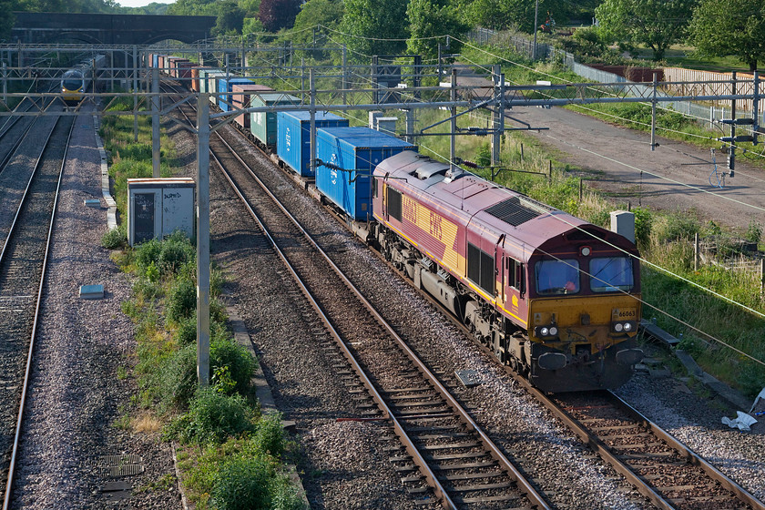 66063, 13.25 Trafford Park-London-Gateway (4L56, 5E) & 390043, VT 16.55 Manchester Piccadilly-London Euston (1A56, 1E), site of Roade station 
 An 'old school' EWS 66063 passes through Roade at the site of the old station, the entrance road of which can be seen in the background. I am staggered that some eleven years after the first EWS locomotive was rebranded to DB that there are still examples such as this one still working in their original as-built livery. The 4L56 13.25 Trafford Park to London Gateway is about to be passed by 390043 heading south with the 16.55 Manchester to Euston Avanti service. 
 Keywords: 66063 13.25 Trafford Park-London-Gateway 4L56 390043 16.55 Manchester Piccadilly-London Euston 1A56 site of Roade station EWS DB Avanti West Coast