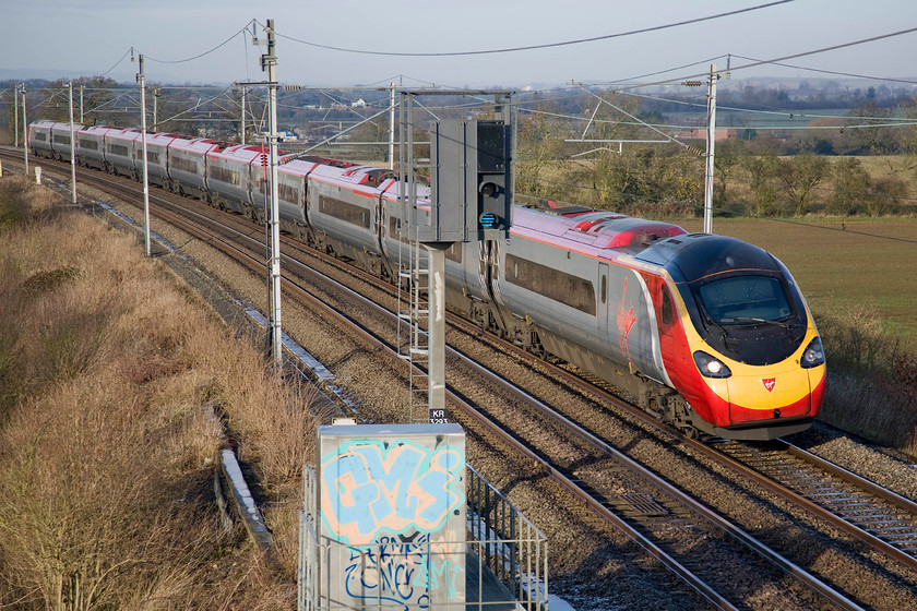 Class 390, VT 08.38 Liverpool Lime Street-London Euston (1A05), Milton crossing 
 I find it amazing that the driver of this Class 390 can actually see out of the windscreen with the blind virtually drawn down to its lowest extent! The Virgin Pendolino is forming the Sunday 08.38 Liverpool Lime Street to Euston 1A05 service and is seen sweeping past Milton Crossing just short of Roade cutting. 
 Keywords: Class 390 VT 08.38 Liverpool Lime Street-London Euston 1A05 Milton crossing Virgin West Coast Pendolino