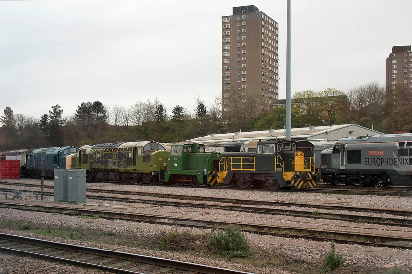 56106, 2 class 37s, D1388, shunter, 37901, stabled, UKRL depot, Leicester 
 Another view of UKRL's Leicester facility taken from our passing train. From left to right, the remains of 56106 is seen minus its cab. There are then two unidentified class 37s (help anybody?) followed by Hudswell shunter D1388. The next shunter remains a mystery. Despite plenty of internet searching, I can find no reference as to what its number is and its history; can anybody help with this please? Finally in this line up is 37901 'Mirrlees Pioneer'. This one of a number of the class that were re-engined by BR in 1986 that were dubbed 'slugs' due to their slow application of their impressive tractive effort. 
 Keywords: 56106 2 class 37s D1388, shunter 37901 UKRL depot, Leicester